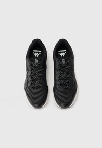 Pair of black athletic shoes with white soles and patterned laces, viewed from above on a light gray background.