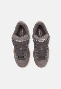 Donkergrijze suède sneakers met rubberen zolen, gestructureerde veters en een gevoerde kraag. Voorzien van een wit logo op de tong.