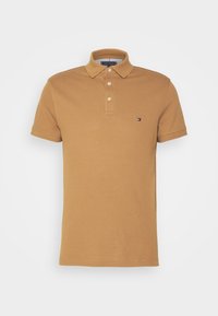 Polo en coton marron avec une patte de boutonnage à trois boutons, manches courtes et un petit logo sur la poitrine gauche. Texture lisse, coupe classique.