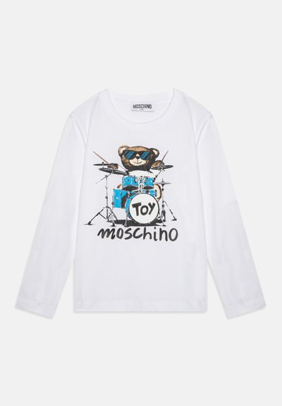 Camiseta blanca de manga larga con un oso con gafas de sol tocando tambores azules y "Toy Moschino" impreso debajo, que destaca un diseño gráfico colorido.