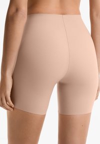 Beżowe szorty bezszwowe wykonane z gładkiego materiału, o długości do połowy uda i wygodnym pasku w talii zapewniającym dobre dopasowanie.