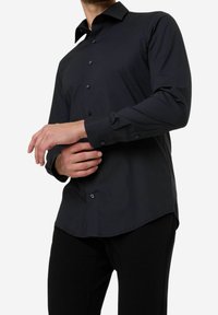 Zwarte button-up shirt met een taillerende pasvorm, lange mouwen, een subtiele glans en contrasterende knopen, voorzien van een spread collar en een afgeronde zoom.