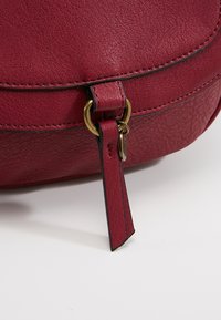 Borsa a tracolla rossa in pelle con finitura strutturata, chiusura in tonalità oro e cuciture a contrasto nere.