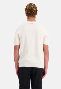 Korte mouwen pullover, gestructureerde witte gebreide stof, geribbelde zoom en kraag, met een label detail op de achterkant van de hals.