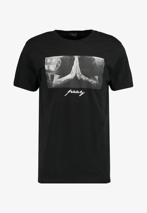 Camiseta negra de manga corta con un gráfico central gris de manos en posición de oración y el texto "pray" debajo en blanco.
