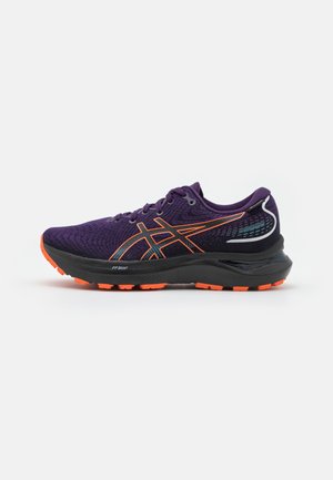 Purple athletic shoe with orange details, textured mesh upper, black midsole, and rubber outsole featuring prominent traction patterns.