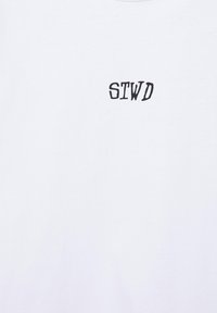 Tissu blanc avec des lettres brodées noires "STWD" centrées près du haut.