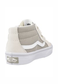 Hoge sneakers met beige canvas en suede materialen, witte zijkleur en klittenbandsluitingen. Dikke witte rubberen zool.