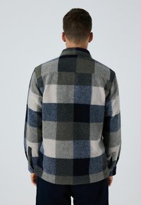Men's checkered flannel shirt featuring a mix of gray, blue, and navy colors. Material appears soft, with a collar and buttoned cuffs.