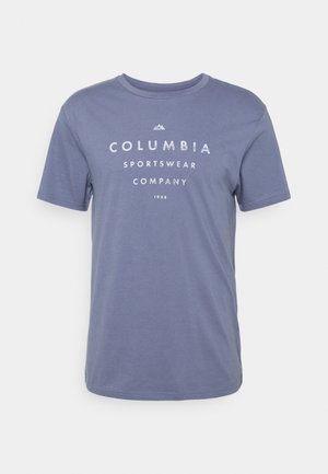Blå t-shirt med korte ærmer og rund hals med hvid tekst "COLUMBIA SPORTSWEAR COMPANY 1938" og et lille bjerglogo over teksten.