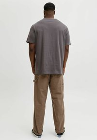Siva bombažna majica s sproščenim krojem, kratkimi rokavi in okroglim izrezom, kombinirana s bež cargo hlačami s stranskimi žepi.