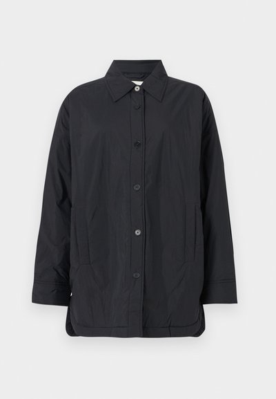 Jachetă ușoară, neagră, cu închidere prin butoni, guler, două buzunare laterale și un tiv ușor curbat. Fabricată dintr-un material neted, mat.