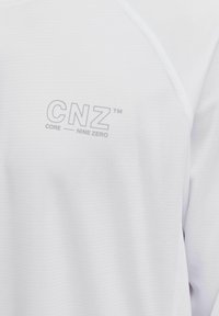 Witte, getextureerde sportshirt met een subtiele "CNZ"-logo en "CORE NINE ZERO"-tekst in lichtgrijs aan de voorkant. Zacht, ademend materiaal.