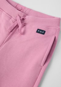 Lyserøde bomulds sweatpants med ribbet talje, justerbar snor og sidelommer. Har en mørkeblå etiket med "P.O.P." logo.