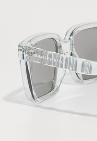 Ochelari de soare din plastic transparent, cu rame pătrate, lentile întunecate și logo-ul embosat "Armani Exchange" pe templele plate. Finisaj lucios.