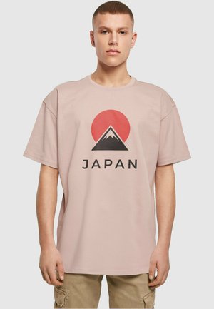 Light pink cotton t-shirt featuring a graphic design of a red sun and mountain silhouette with the text "JAPAN" in bold black letters.