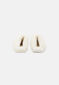 White plush slippers with open back, soft fur-like texture, flat sole, and rounded shape. No visible patterns or hardware details.