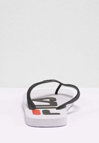 Sort gummisandal med en struktureret rem, hvid sål, fed "FILA" logo i sort og en rød accent på hælen.