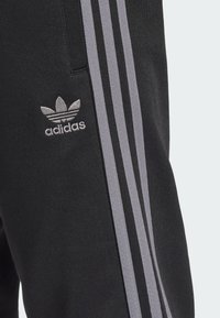 adidas Originals Spodnji deli trenirk - black   grey four