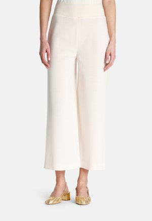 Pantaloni cream a gamba larga con una vita a coste testurizzata. Abbinate a sandali con tacco a blocco metallici. Tessuto morbido e silhouette fluida.