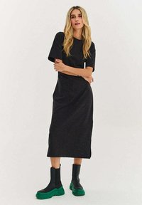 Mustast lühikeste varrukatega midi-kleit, millel on lihtne disain ja peened täpid. Sobitatud robustsete mustade ja roheliste platvorm-saabastega.