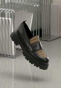 Schwarze Lederloafers mit einem gemusterten braunen Textil-Vorderteil, ausgestattet mit einer klobigen schwarzen Sohle und einem breiten Riemen über dem Spann.