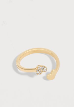 Inel deschis din aur, cu un capăt în formă de inimă decorat cu mici pietre prețioase transparente, iar celălalt simplu, pe fundal alb.