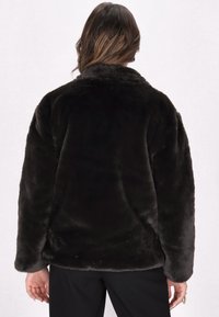 Mørkebrun faux fur-jakke med en blød tekstur, oversized pasform og en rund krave, der har sømløse ærmer og et lige rygdesign.