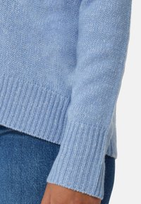 Světle modrý pletený svetr s žebrovanými manžetami a lemem. Měkká textura s mírně volným střihem, který ukazuje ležérní design.