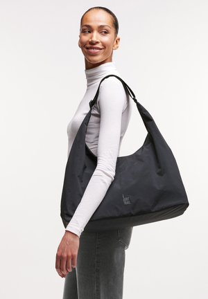 Sort nylon skuldertaske med et blødt, struktureret design, der har en bred rem og et trykt logo. Glat tekstur og rummeligt indre.