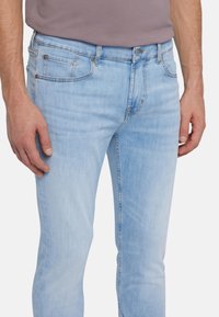 Jeans in denim azzurro chiaro con una vestibilità slim, dotati di cinque tasche, leggera scoloritura e parti in metallo per la chiusura e i dettagli.