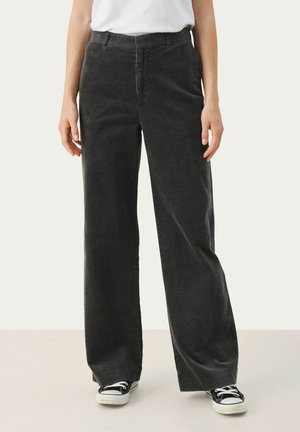 Pantalons larges en velours côtelé gris foncé avec texture à côtes surélevées et poches avant, associés à des baskets basses noires.
