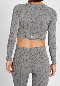 Top ajustado de manga larga color gris con un patrón texturizado, dobladillo acanalado y leggings de color gris de cintura alta a juego con un detalle de patrón similar.