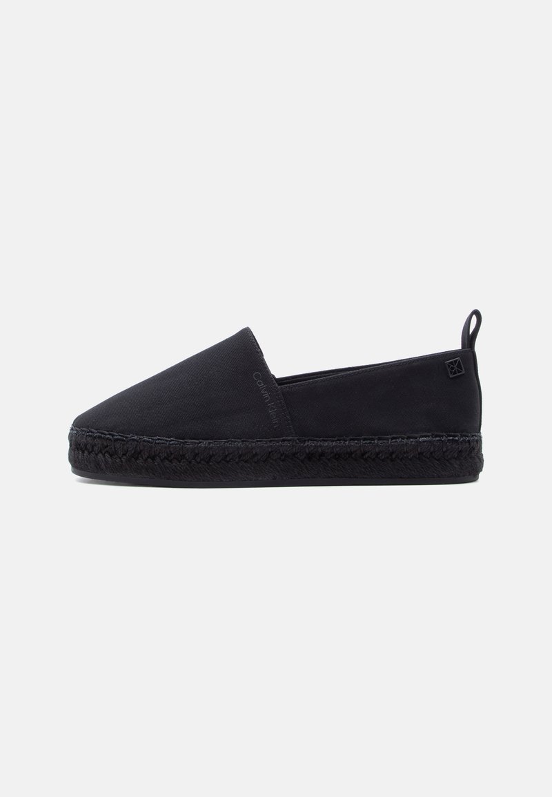 Espadrille noire à enfiler avec semelle tressée, dessus en tissu, languette à l'arrière et discrète marque Calvin Klein sur le côté.