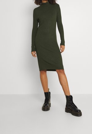 Robe midi côtelée vert foncé à manches longues et col montant, associée à des bottes de combat noires à lacets avec une semelle épaisse.
