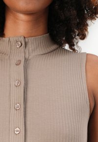 Ribbed, sleeveless top in light brown, featuring a high collar and five front buttons in a matching shade, with a smooth texture.