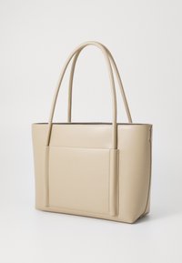 Borsa tote in finta pelle beige con due lunghe maniglie, forma rettangolare e una tasca frontale. Texture liscia con dettagli di cucitura sottili.