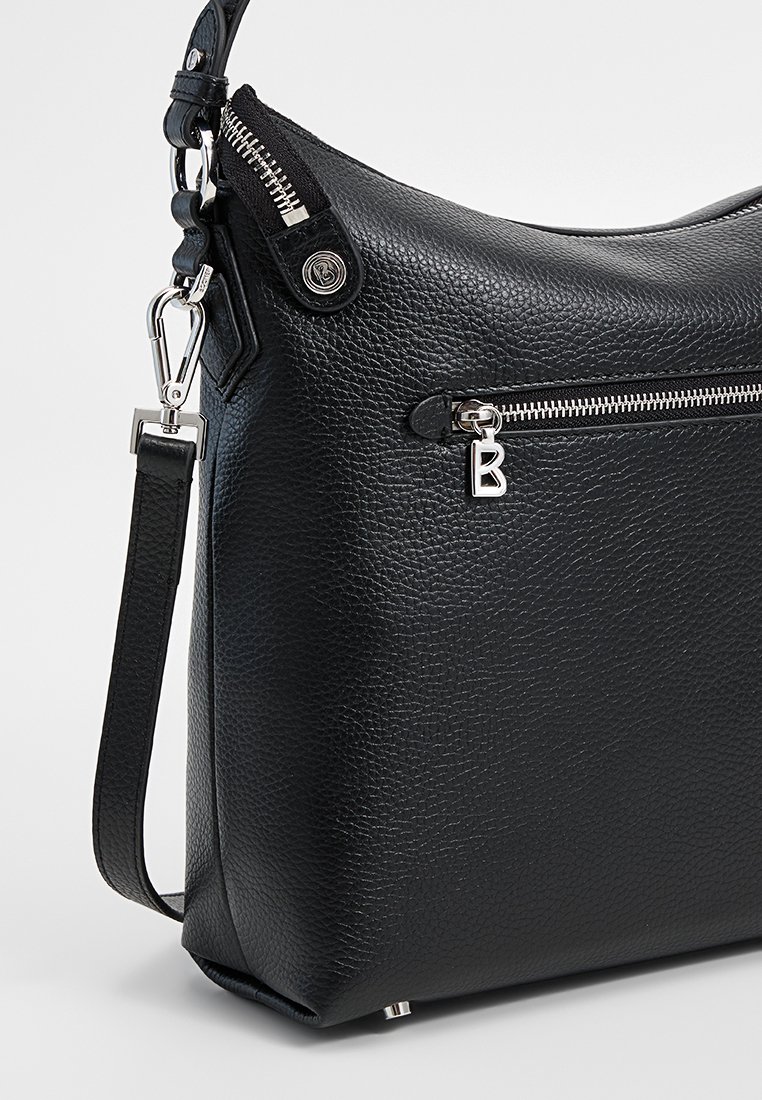 Schwarze Leder Schultertasche mit strukturierter Oberfläche, ausgestattet mit einem silbernen Reißverschluss, einem dekorativen "B"-Anhänger und einem verstellbaren Schulterriemen.