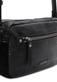 Bolso crossbody de cuero negro con un acabado texturizado, que cuenta con un bolsillo con cremallera en la parte frontal, herrajes plateados y un detalle del logotipo.