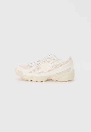 Light beige athletic shoes with mesh upper, white accents, round toe, low profile, and textured rubber sole. Laces are white.