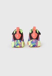 Zapatillas deportivas multicolores con parte superior negra, detalles en amarillo neón y una suela texturizada y con patrones en tonos vibrantes de azul, rosa y verde.