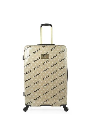 Maleta rígida en color beige con un estampado negro del logo de DKNY. Cuenta con un mango retráctil, herrajes dorados y cuatro ruedas giratorias para mayor movilidad.