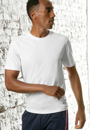 White cotton t-shirt with short sleeves, round neck, and a fitted design. Features a logo accent on the lower side.