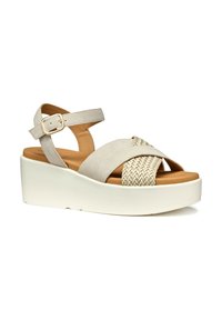 Sandali con tacco a cuneo beige con dettagli intrecciati, cinturino alla caviglia regolabile, parte superiore in morbido suede e suola bianca. Superficie testurizzata, design minimale.