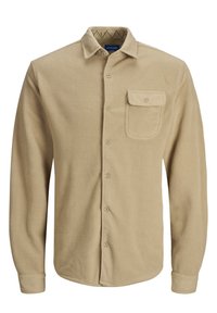 Beżowa koszula z polaru zapinana na guziki, z ostrym kołnierzem, pojedynczą kieszenią na piersi oraz miękką fakturą. Posiada guziki z przodu i na mankietach.