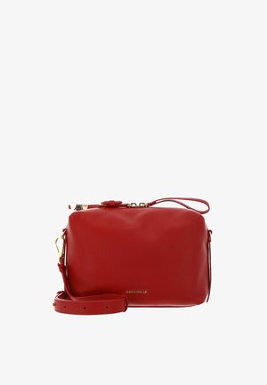 Sac bandoulière en cuir rouge avec sangle réglable, ferrures dorées, fermeture éclair et logo "Coccinelle" sur le devant.