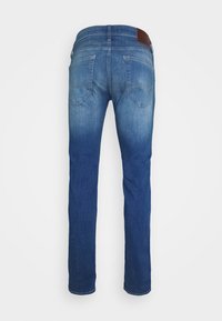 Schlanke blaue Denim-Jeans mit leichter Verwaschung, zwei Gesäßtaschen und einem braunen Lederpatch am Bund.
