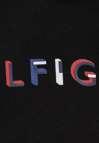 Svart stoff med store, flerfargede bokstaver som staver "LFIG." Bokstavene har røde, blå og hvite detaljer, med en teksturert finish.