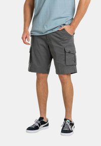 Pantalones cortos de carga grises con dos bolsillos laterales, confeccionados en una mezcla de algodón. Combinados con zapatillas negras y una camiseta de color azul claro.