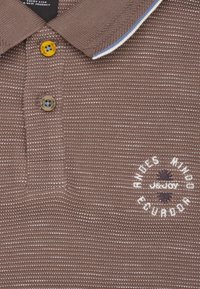 Bruin getextureerd poloshirt met een gestreept patroon, voorzien van een gele en twee-kleurige knopen, en geborduurde 'Andes Mindo Ecuador' details.